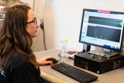 A student sits in front of a computer monitor that displays graphical data from a chemistry experiment